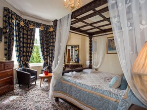 A bedroom with a canopy bed, a wooden dresser, a chair, and a small table. - The Elmington Hotel (Torquay)