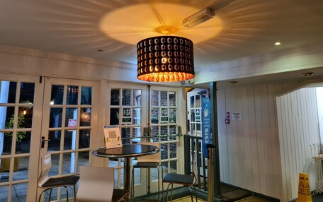 A room with a round table, two chairs, a hanging light fixture, and a door with a sign indicating a fire exit.