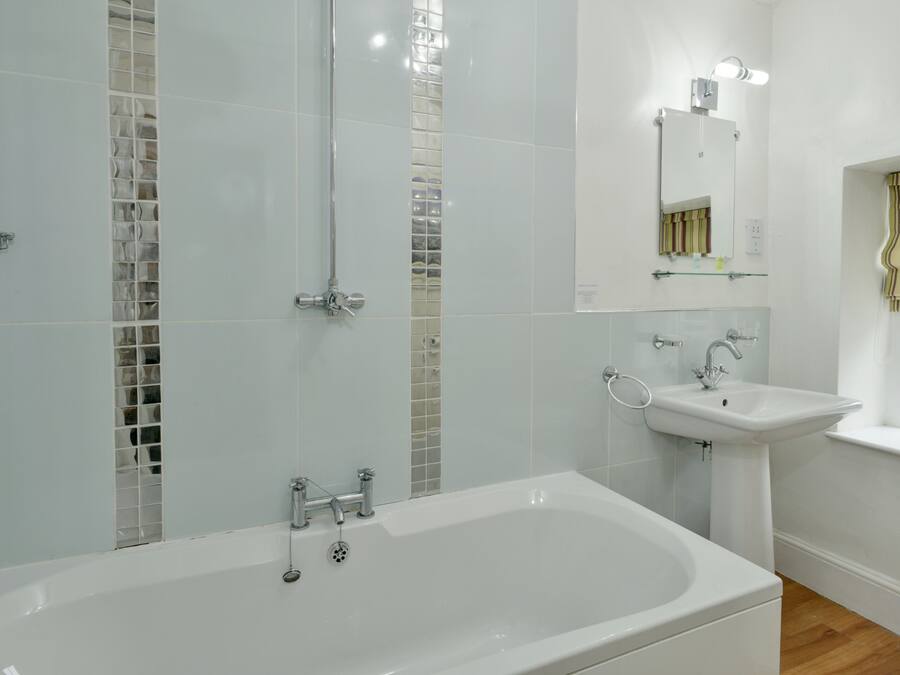 A modern bathroom with a large bathtub, a sink, and a shower area.