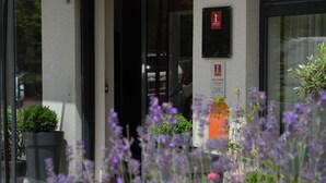 A hotel entrance with a glass door, a plaque indicating the hotel name, and a sign for the concierge. - Villa Val Sénart (Quincy-sous-Senart)