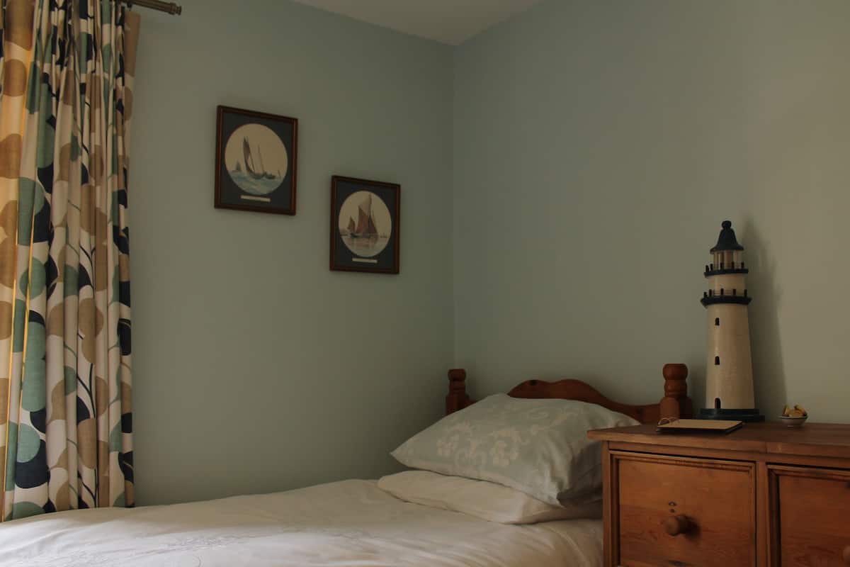 A bedroom with a bed, a dresser, a nightstand, and two framed pictures on the wall.