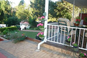 A covered outdoor area with a white railing, potted plants, and a bicycle.