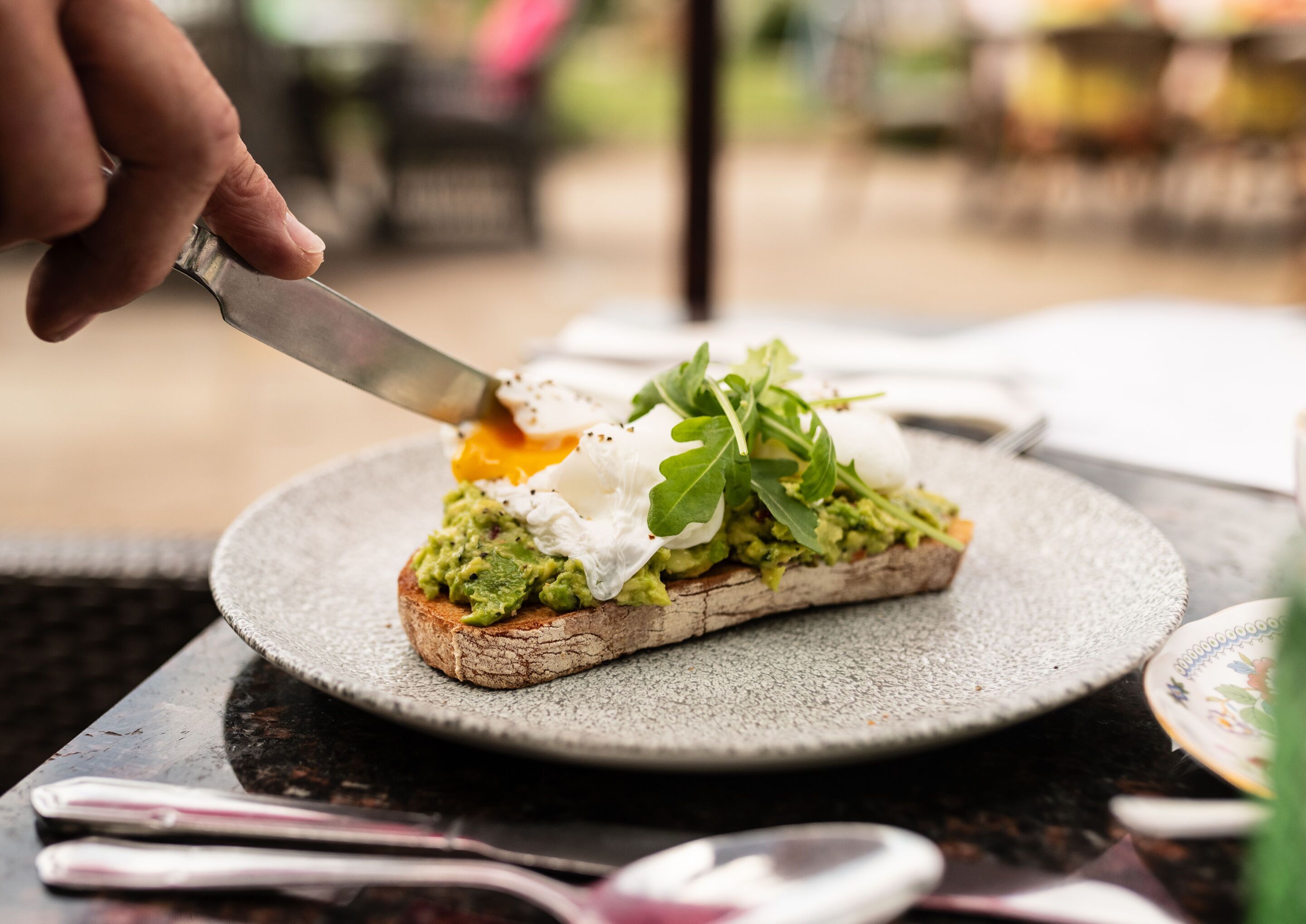 A person cutting a sandwich on a round plate.