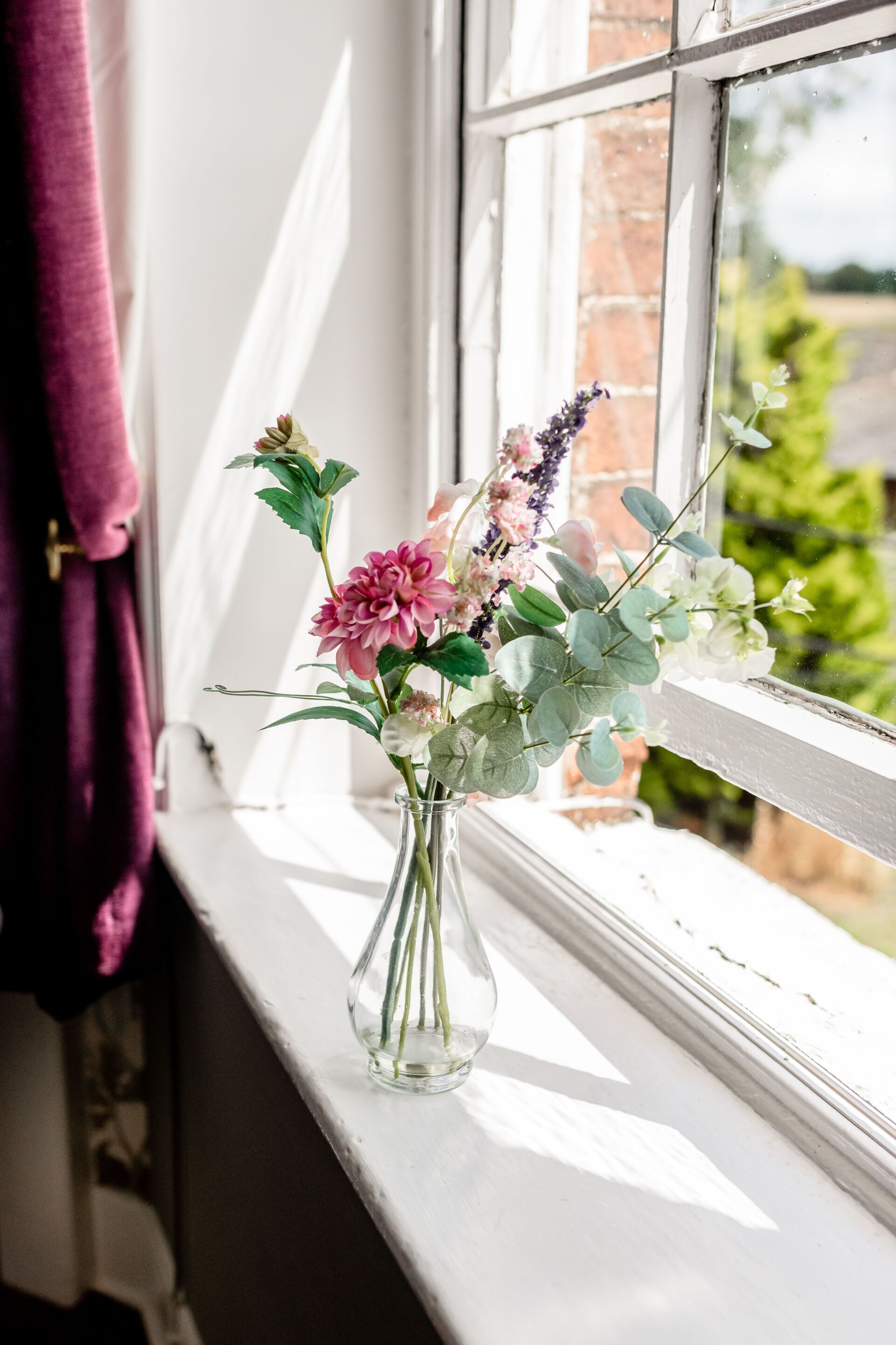 A clear view of a window with a vase of flowers on the sill.
