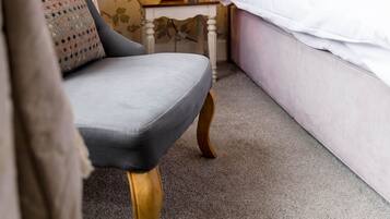 A hotel room with a bed, a chair, a nightstand, a lamp, and a mirror.