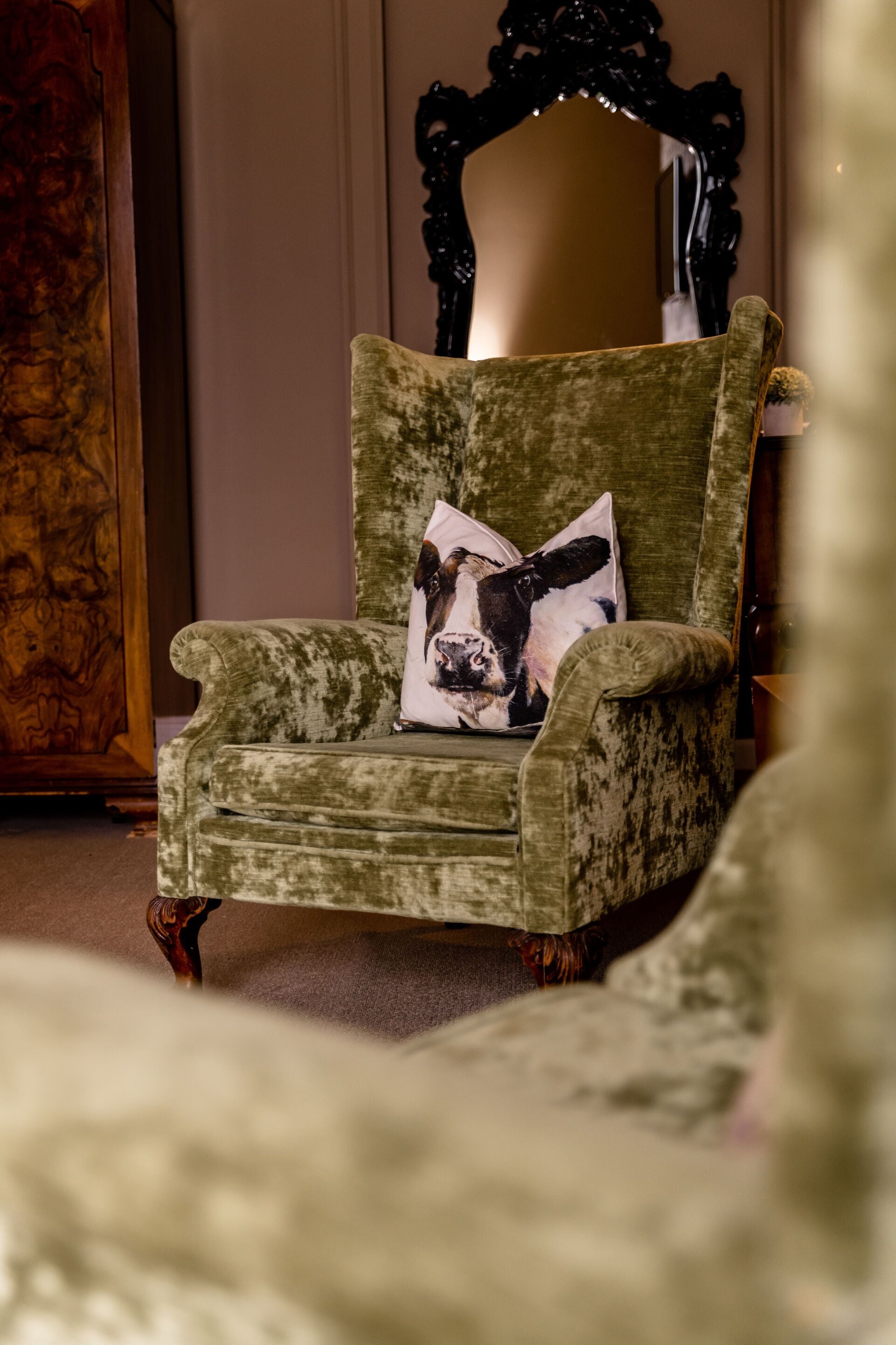 A green upholstered armchair with a cushion featuring a dog print.