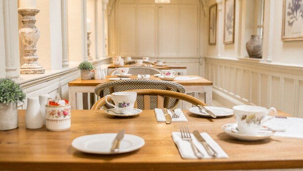 A dining area with a long table, chairs, and hanging pendant lights. - Sweeney Hall Hotel (Oswestry)