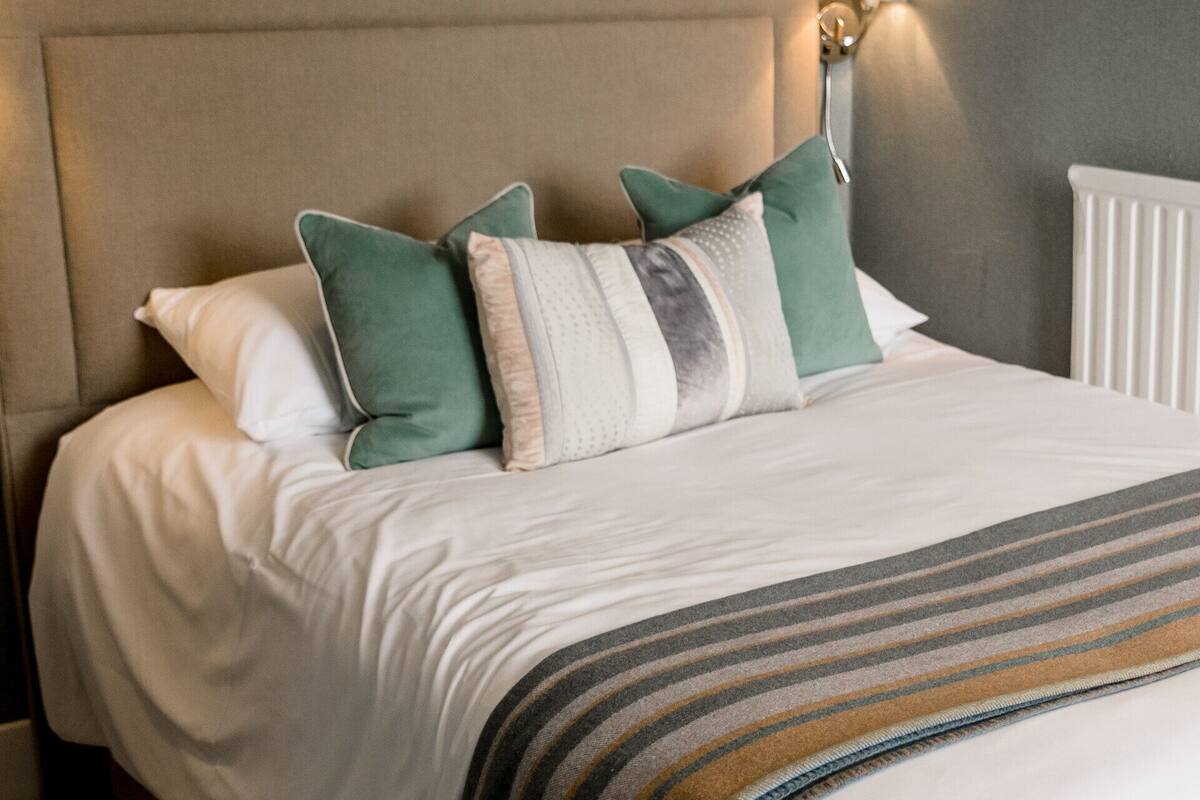 A neatly made bed with a striped throw blanket, a headboard, and multiple pillows.