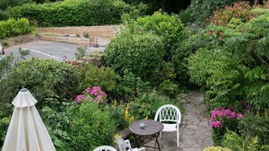 A patio with stone flooring, white chairs, and a table. - Southern Cross Guest House (Sidmouth)