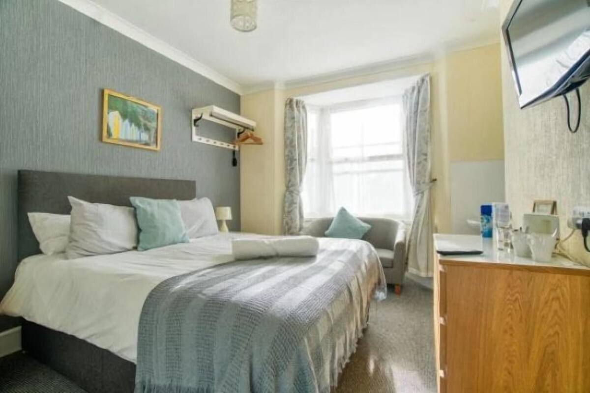 Een hotelkamer met een bed, een bureau, een stoel, een televisie en een raam met gordijnen.