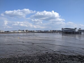 A coastal area with a pier extending into the water, buildings in the background, and a clear sky. - The Parasol Weston (Weston-super-Mare)