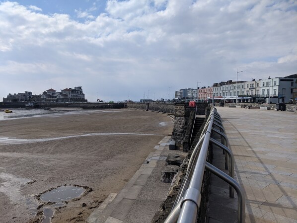 A beach with a stone wall and a metal railing. - The Parasol Weston (Weston-super-Mare)