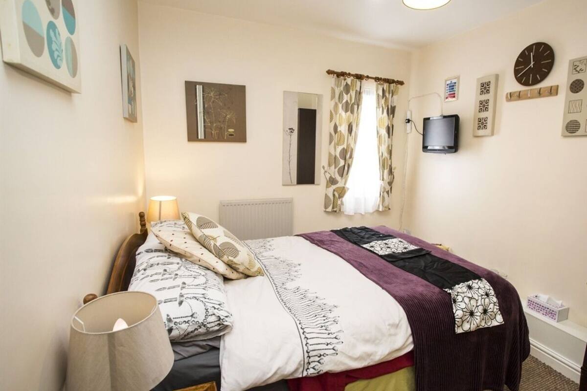 Un dormitorio con cama, lámparas de noche, un reloj y adornos en la pared.
