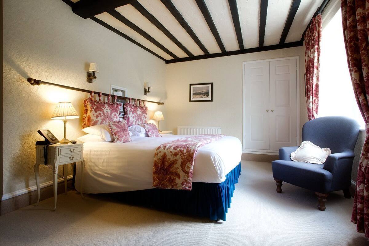 A bedroom with a bed, bedside table, lamp, chair, and a white door.