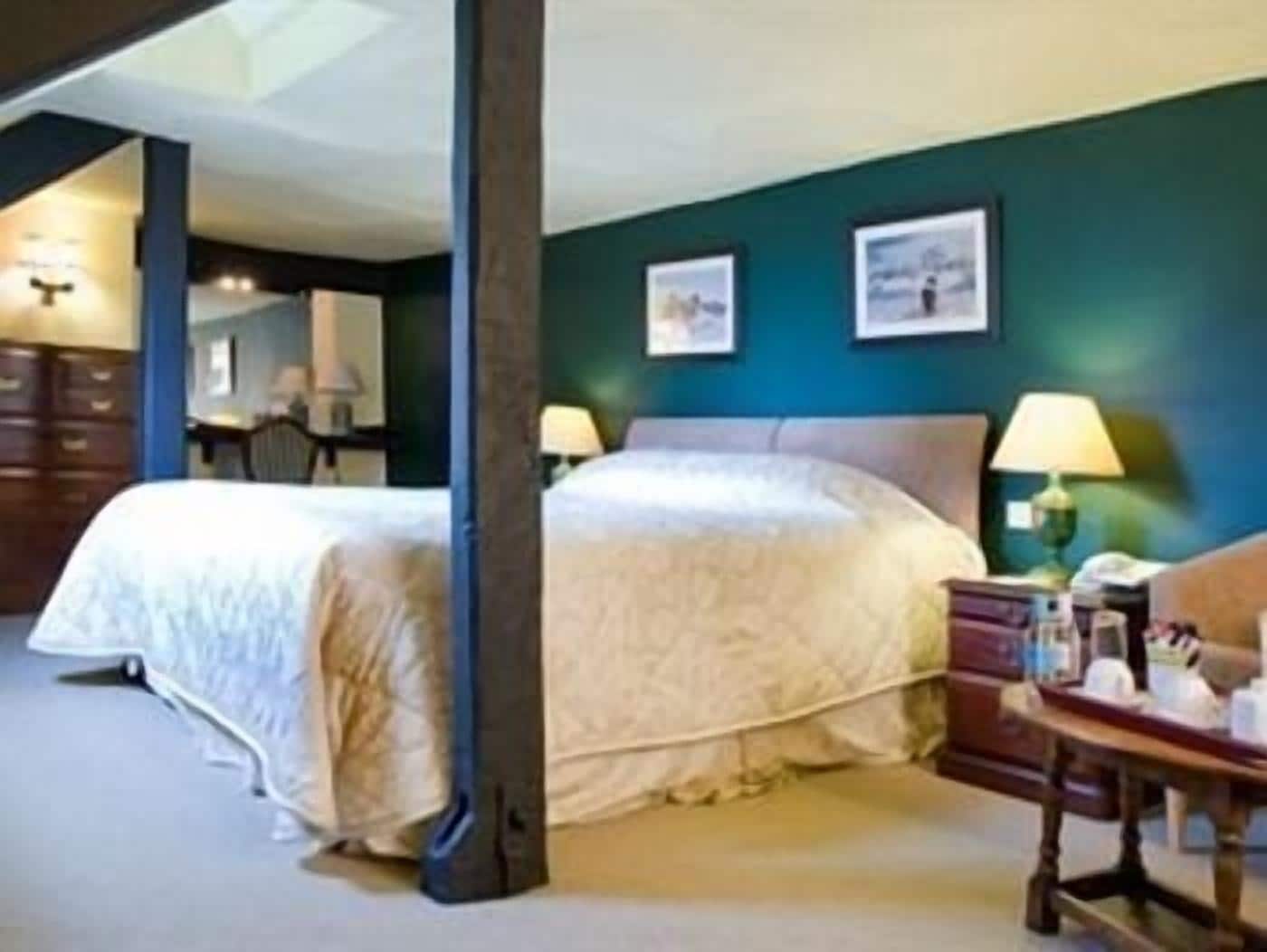 Une chambre d’hôtel avec deux lits, un bureau avec une lampe et des œuvres d’art accrochées au mur.