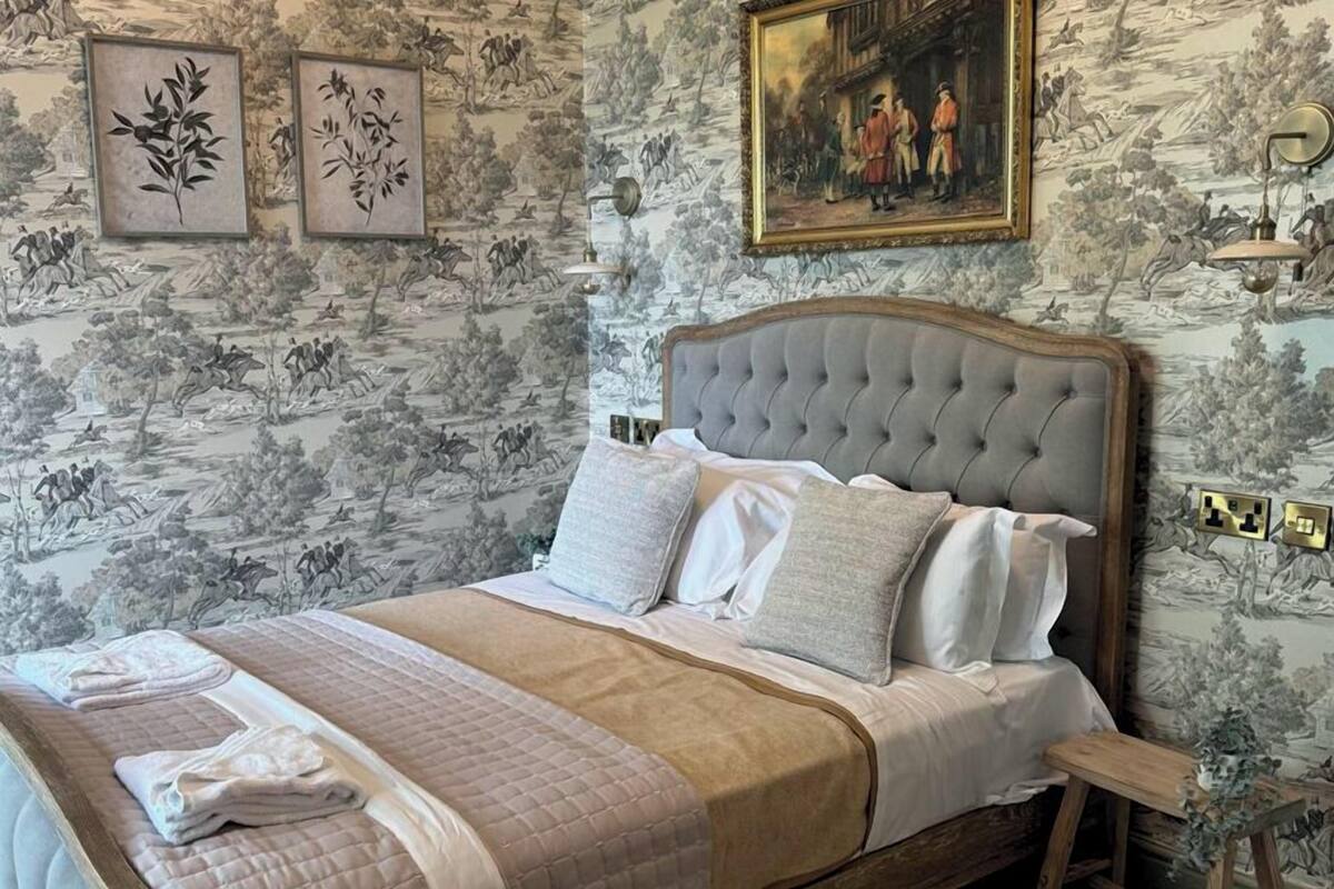 A bedroom with a large bed, a headboard, and a nightstand with a lamp.