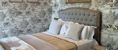 A bedroom with a large bed, a headboard, and a nightstand with a lamp.