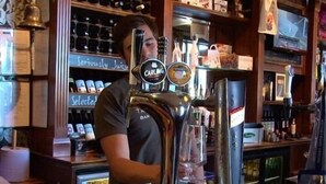 Un bar avec une tireuse portant l’inscription « CARLING » et une sélection de boissons en bouteille exposées sur des étagères.