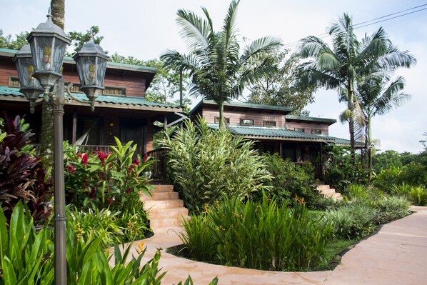 A traditional building with a green roof, surrounded by lush greenery and palm trees. - Blue River Resort & Hot Springs (Guayabo)
