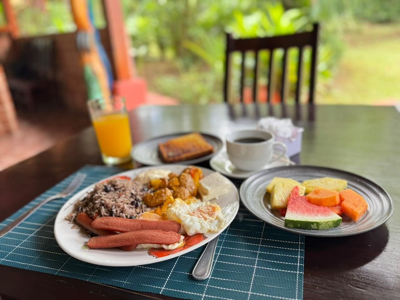 A breakfast setting with a plate of food, a glass of orange juice, and a cup of coffee on a table.