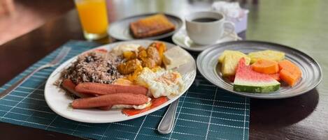 A breakfast setting with a plate of food, a glass of orange juice, and a cup of coffee on a table.