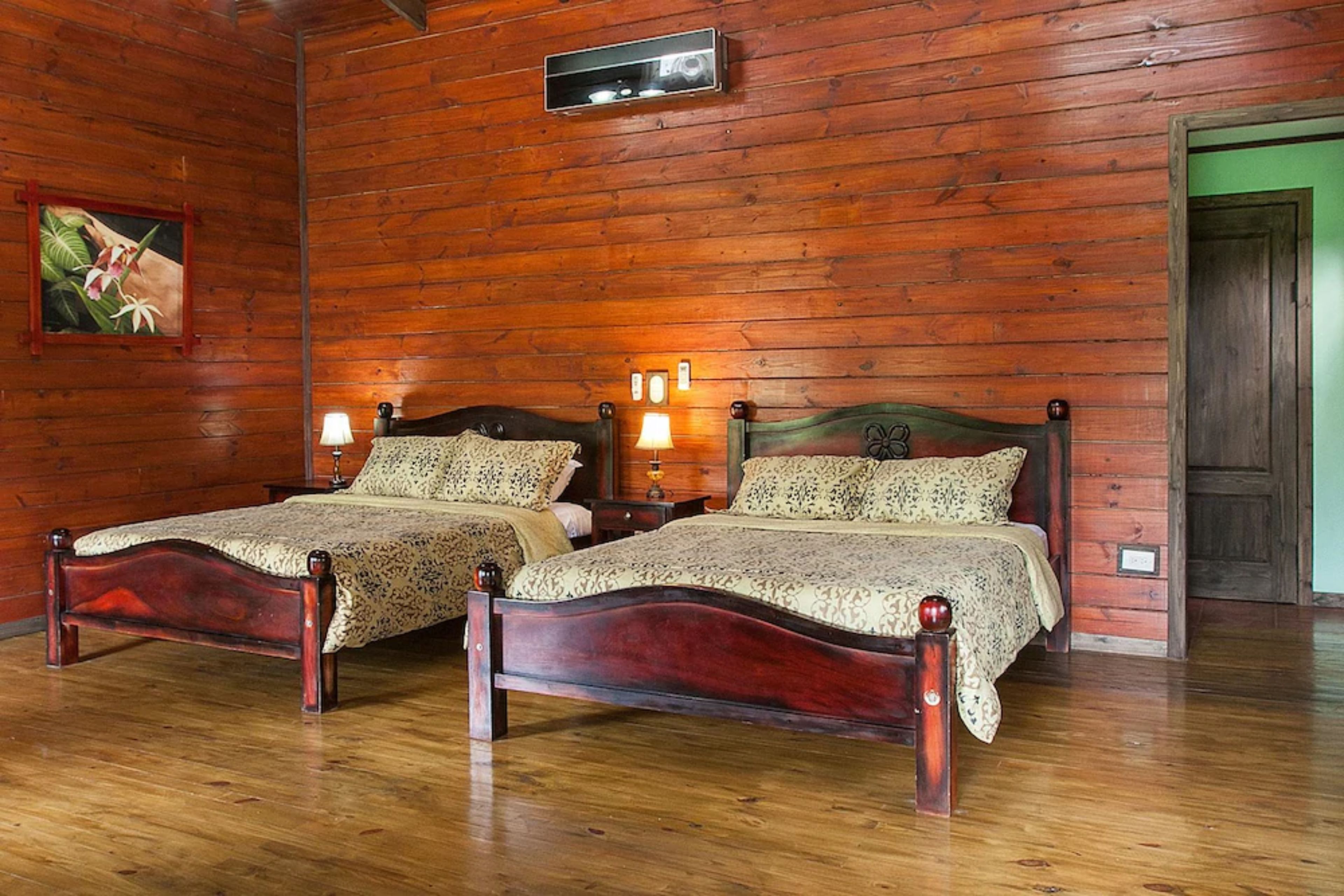 A room with two wooden beds, a wooden ceiling, and a green door.