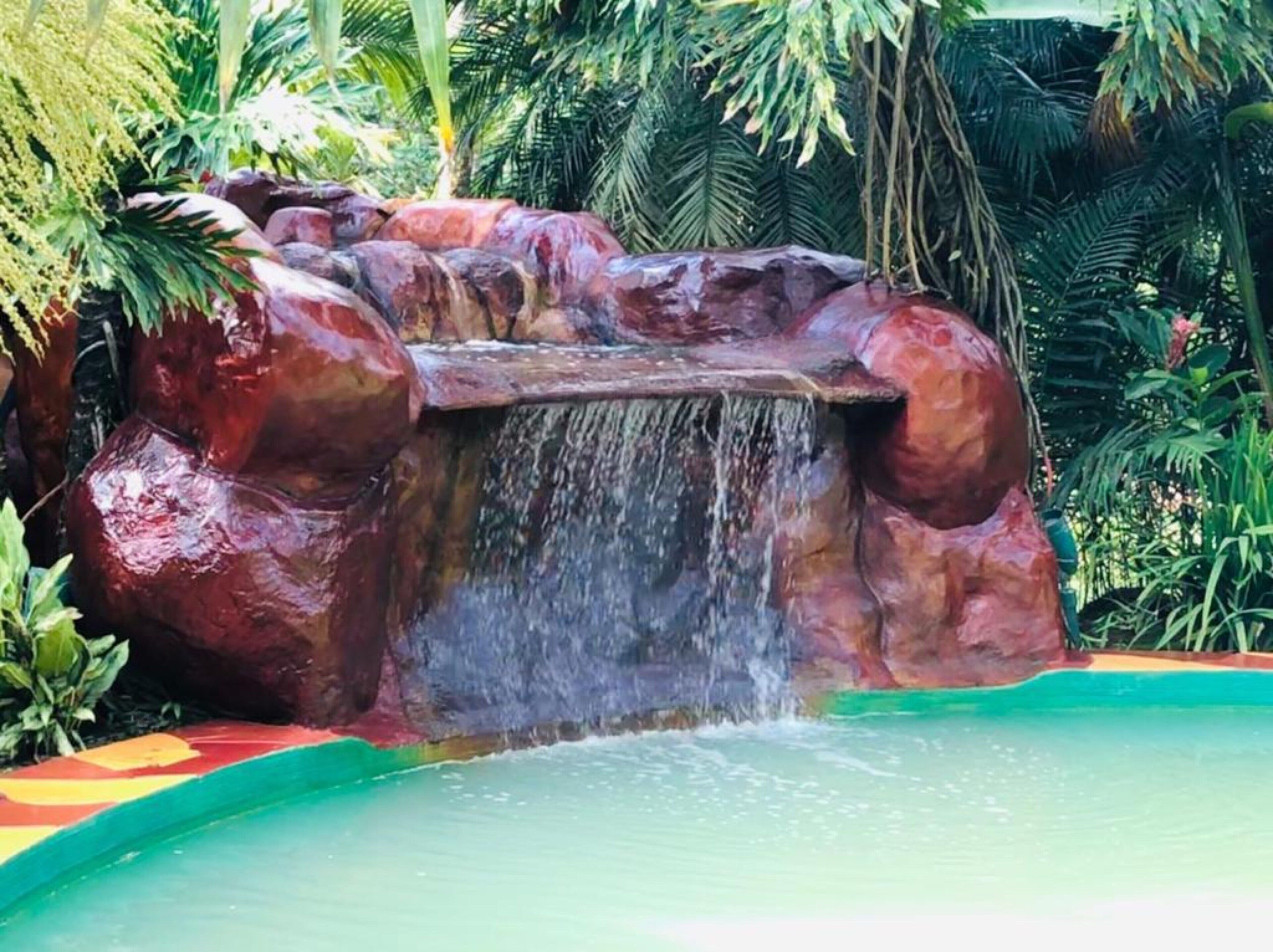 Una cascada con una piscina natural en la base, rodeada de abundante vegetación.