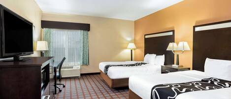 A hotel room with two beds, a TV, a desk, and a window with curtains.