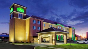 A multi-story hotel with a prominent entrance, a sign indicating it is a La Quinta Inn & Suites, and a parking lot with cars.