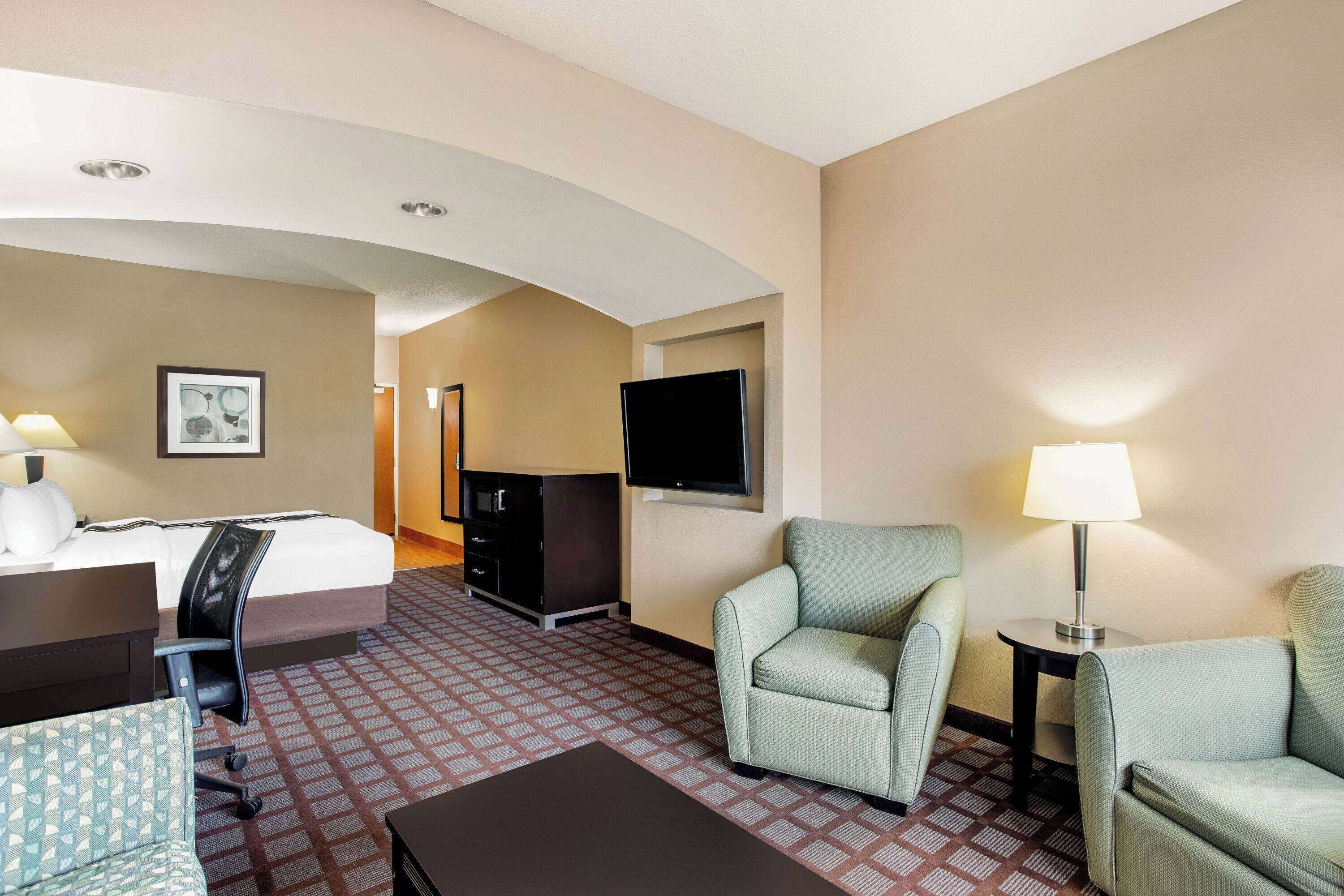 Una habitación de hotel con cama, escritorio, sillas, televisor y lámpara.