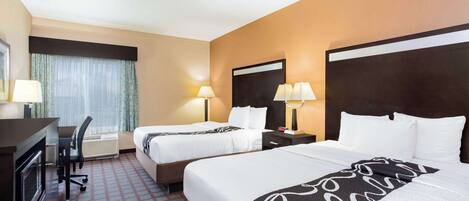 Une chambre d’hôtel avec deux lits, un bureau et une chaise.