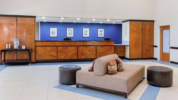 A lobby with a reception desk, a sofa, and two ottomans.