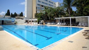 Une piscine avec des chaises longues et un bâtiment en arrière-plan.