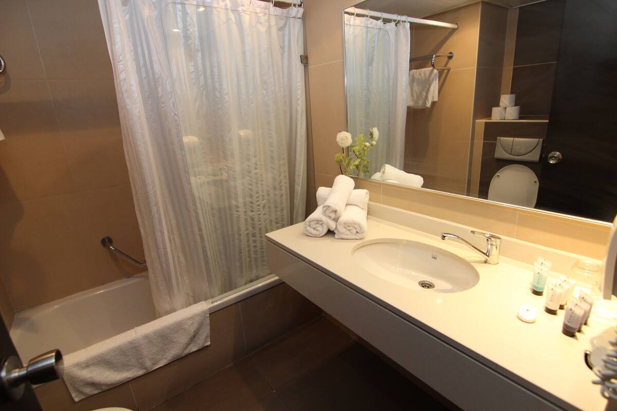 Une salle de bain avec une baignoire, un lavabo équipé de produits de toilette et un miroir.