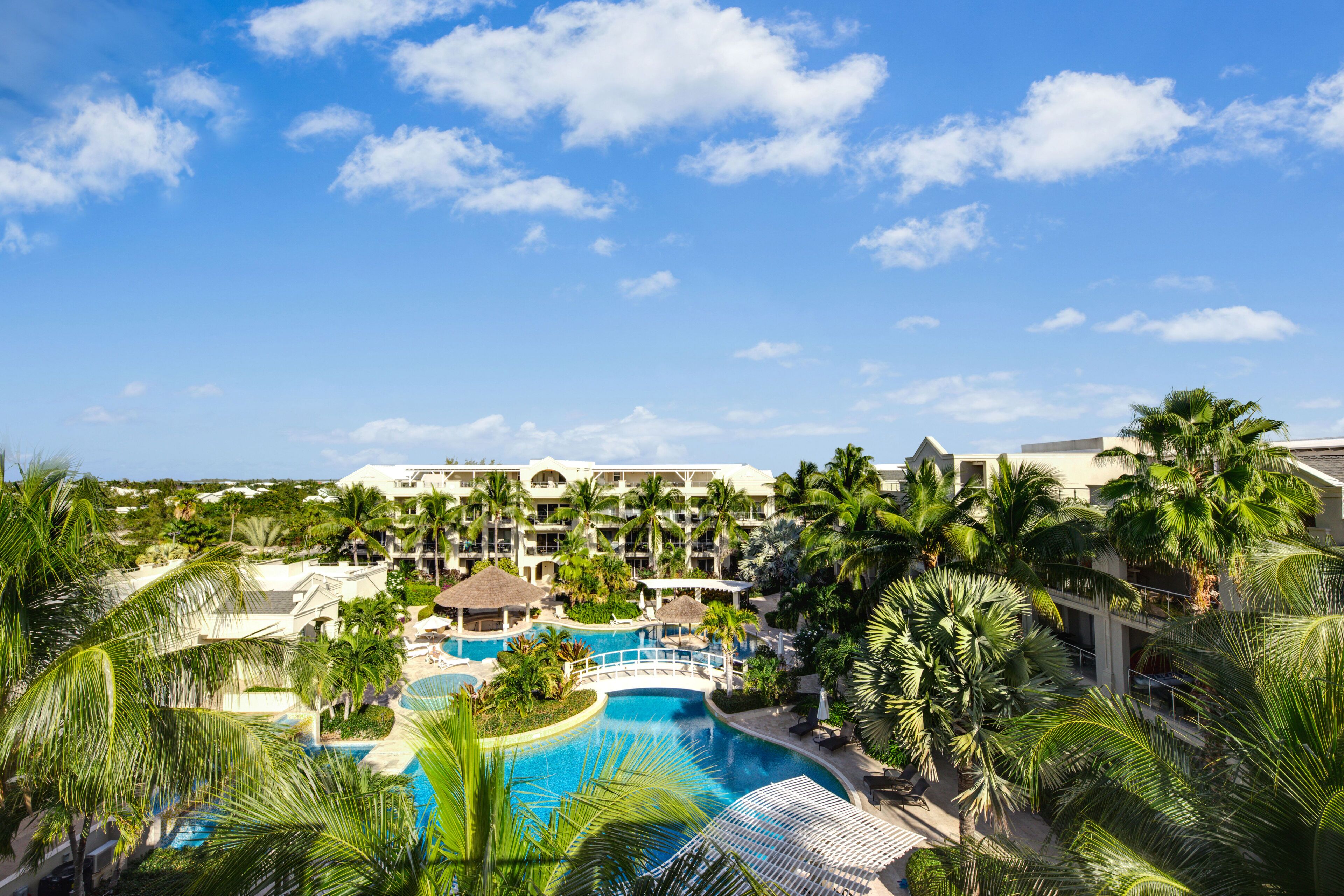 A resort with multiple swimming pools, palm trees, and a large building with multiple balconies.