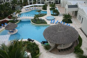 A resort pool area with multiple swimming pools, lounge chairs, and palm trees. - The Atrium Resort (Providenciales)