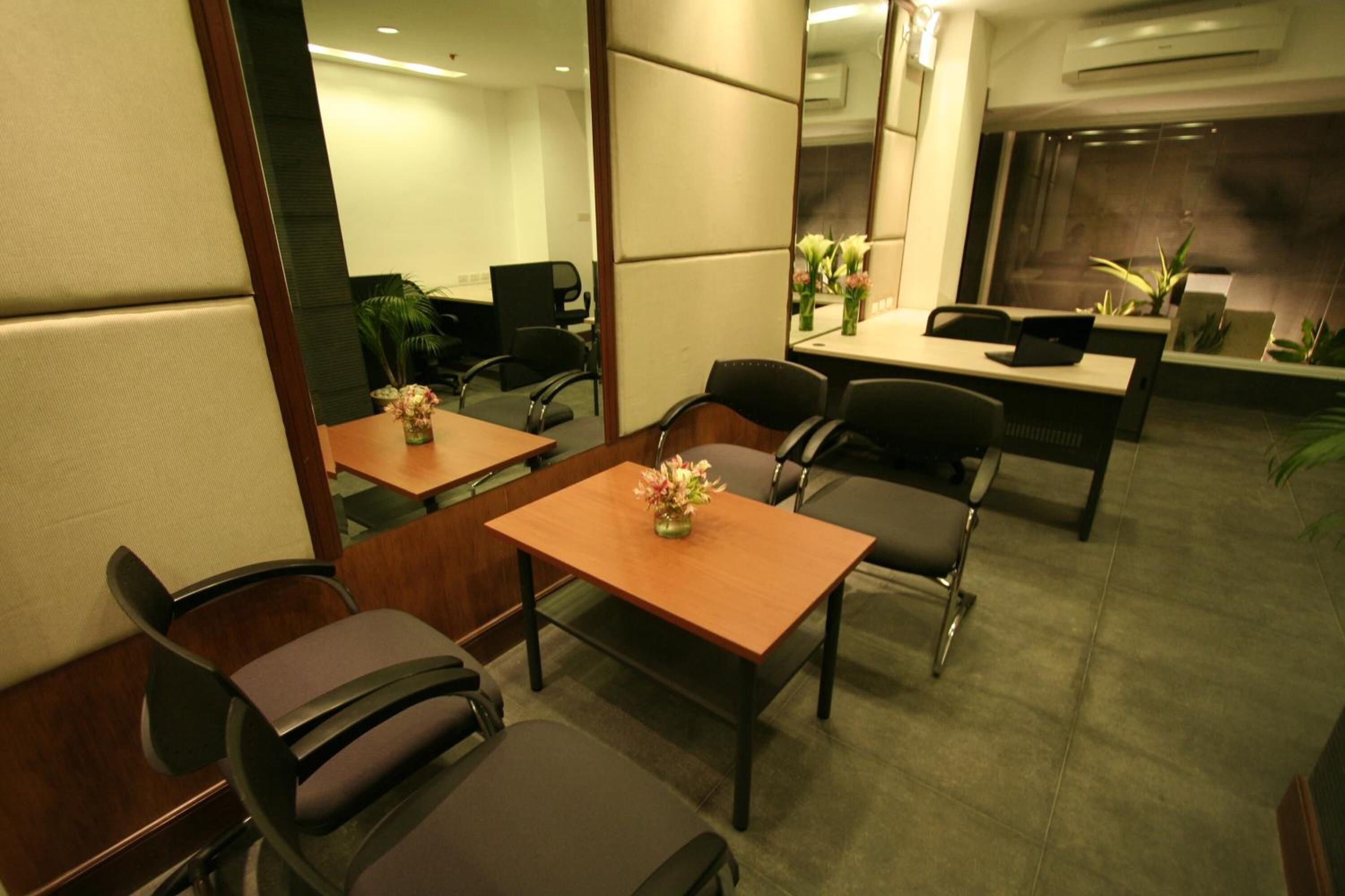 A conference room with a wooden table, black chairs, and a vase with flowers.