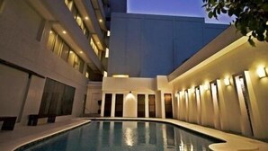 A modern hotel courtyard with a swimming pool, multiple balconies, and a well-lit exterior. - Hotel St Ellis (Legazpi)