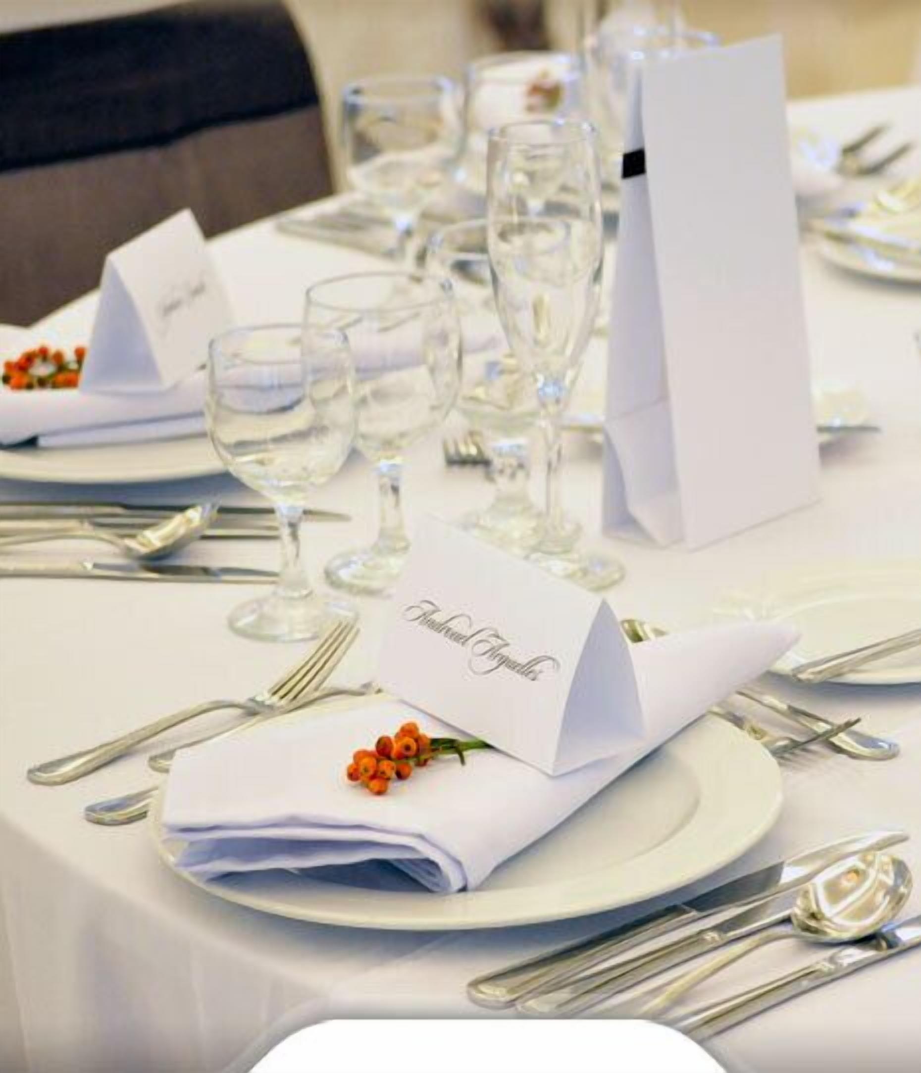 A table set for a formal dining occasion with folded napkins, wine glasses, and silverware.