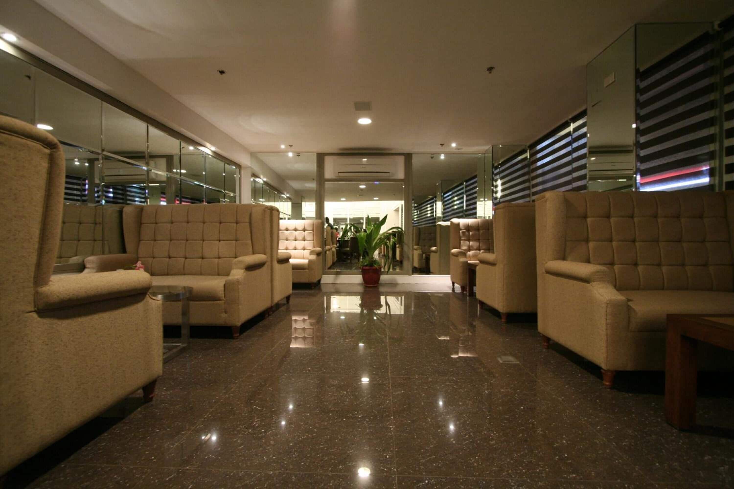 A lobby with plush seating, a central plant, and a mirrored wall.