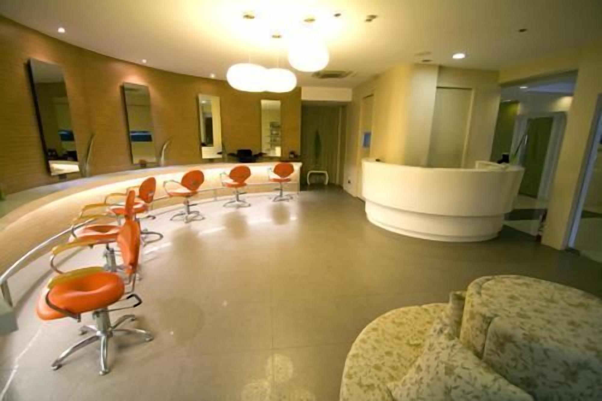 Een receptiezone met een gebogen bureau, meerdere oranje stoelen en een gestreept bankje.
