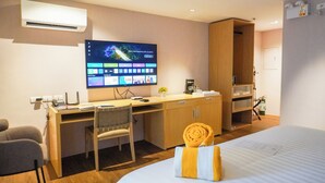 A hotel room with a wooden desk, a chair, a bed, and a large screen displaying a user interface. - Hotel St Ellis (Legazpi)
