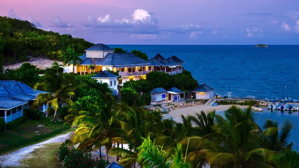 A coastal property with a large house, smaller buildings, and a beach.