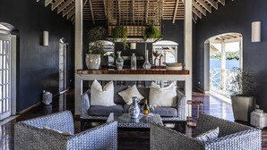 A spacious room with a high ceiling, wicker furniture, and a wooden ceiling structure.