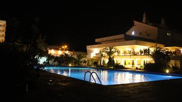 Una piscina al aire libre, sombrillas, tumbonas