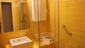 Un baño con ducha vidriada, lavamanos y un perchero para toallas.
