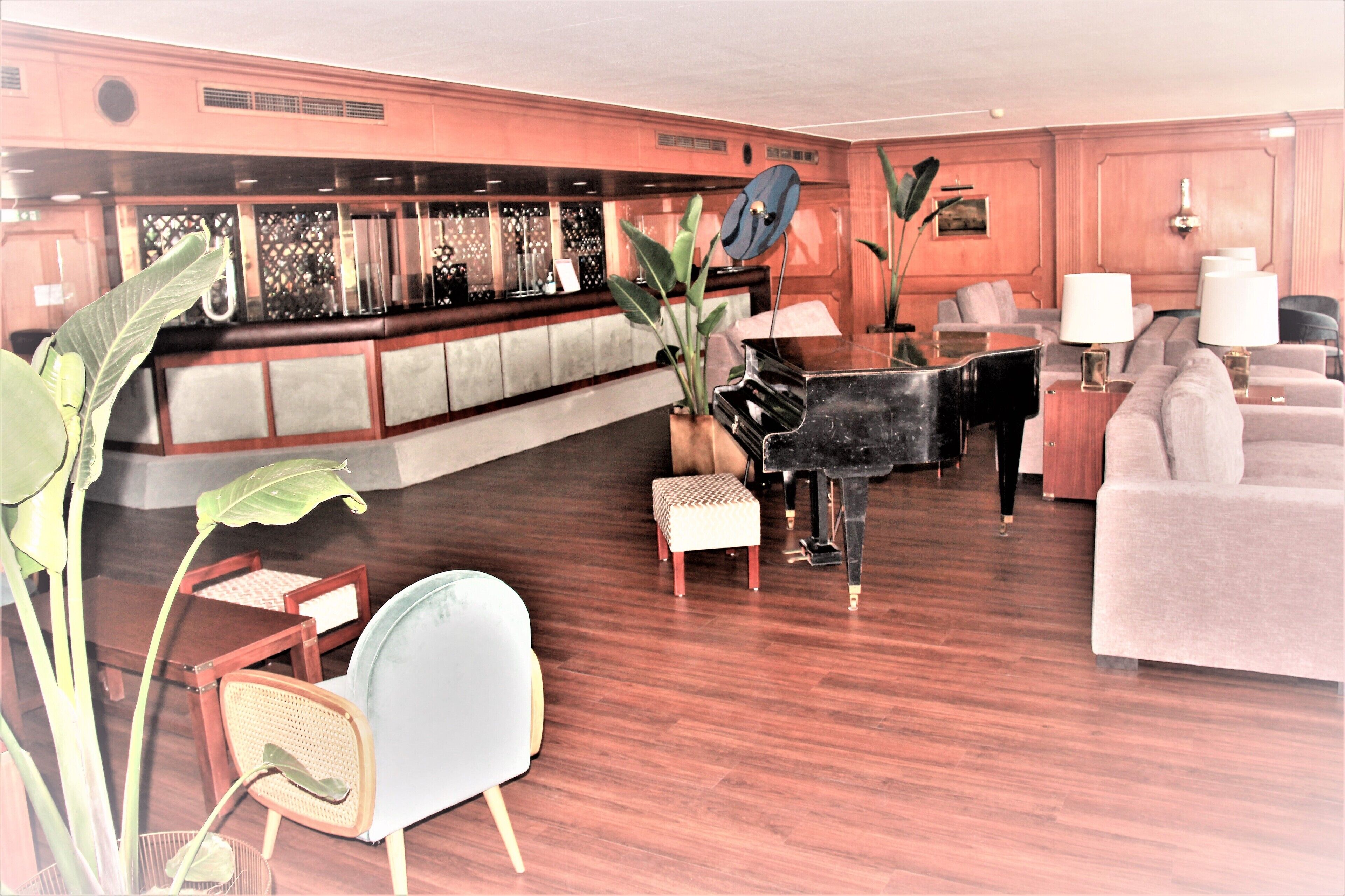 A spacious living room with a grand piano, a comfortable sofa, and a bar area with a piano.