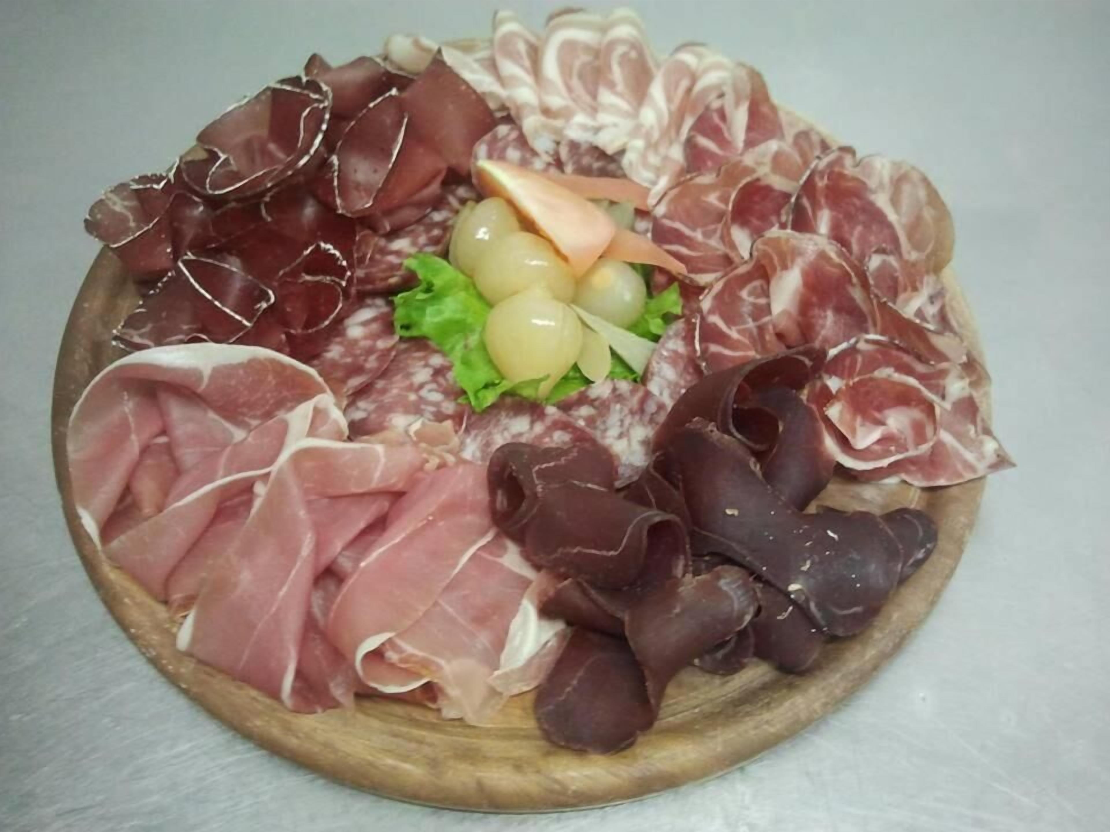 Une planche de charcuterie avec différentes sortes de viandes et de fromages.