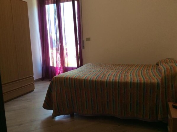 Un dormitorio con cama, armario de madera y ventana con cortinas.