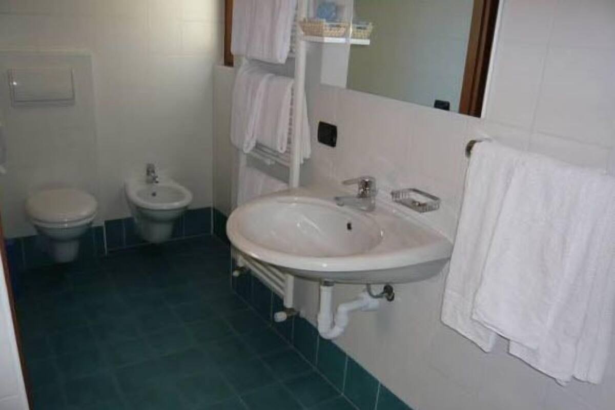 A bathroom with a sink, two toilets, and a mirror.